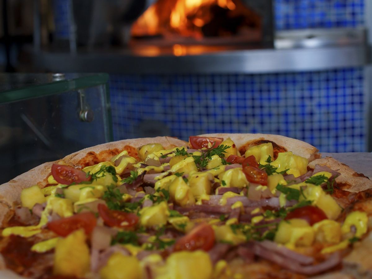 Close-up of the Ham di Pasku Christmas pizza with roasted pineapple, red onion and piccalilli drizzle